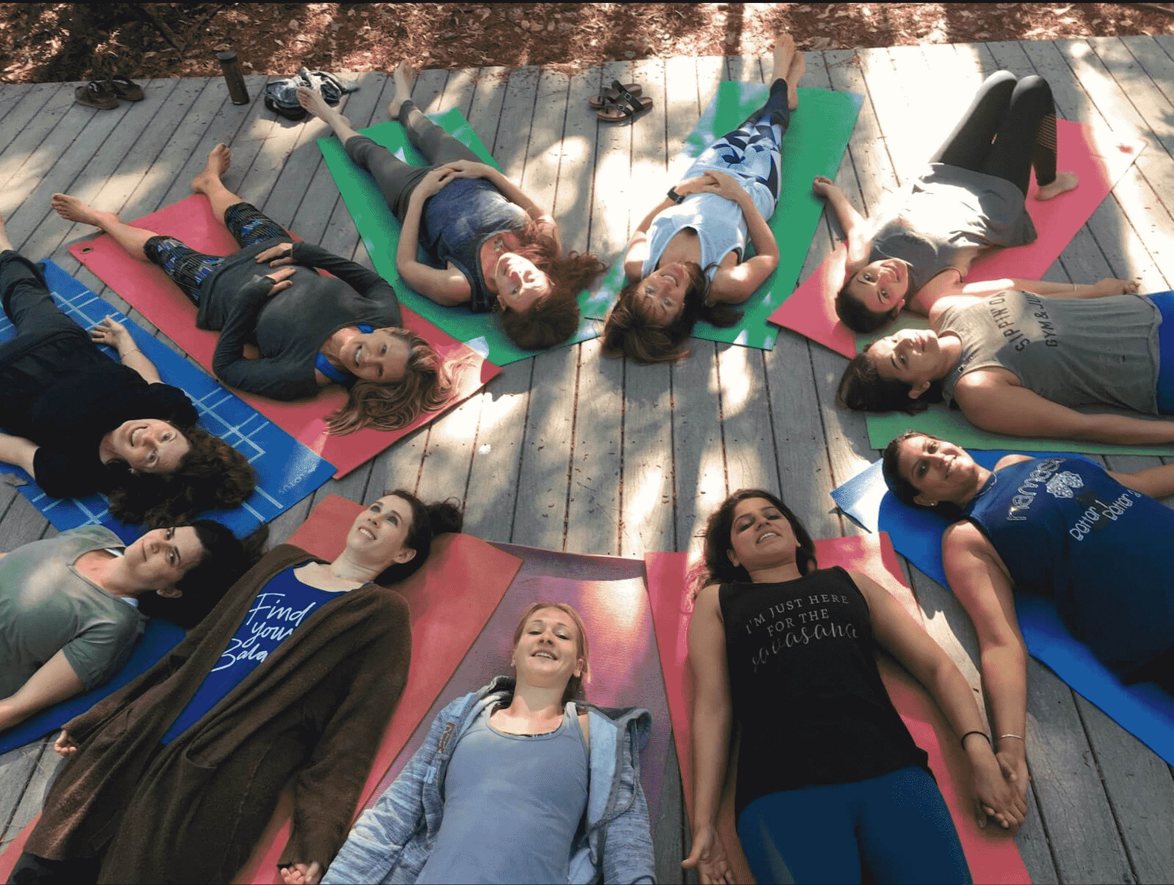 Women lying in a circle and holding hands outdoors at a mindfulness retreat in Texas